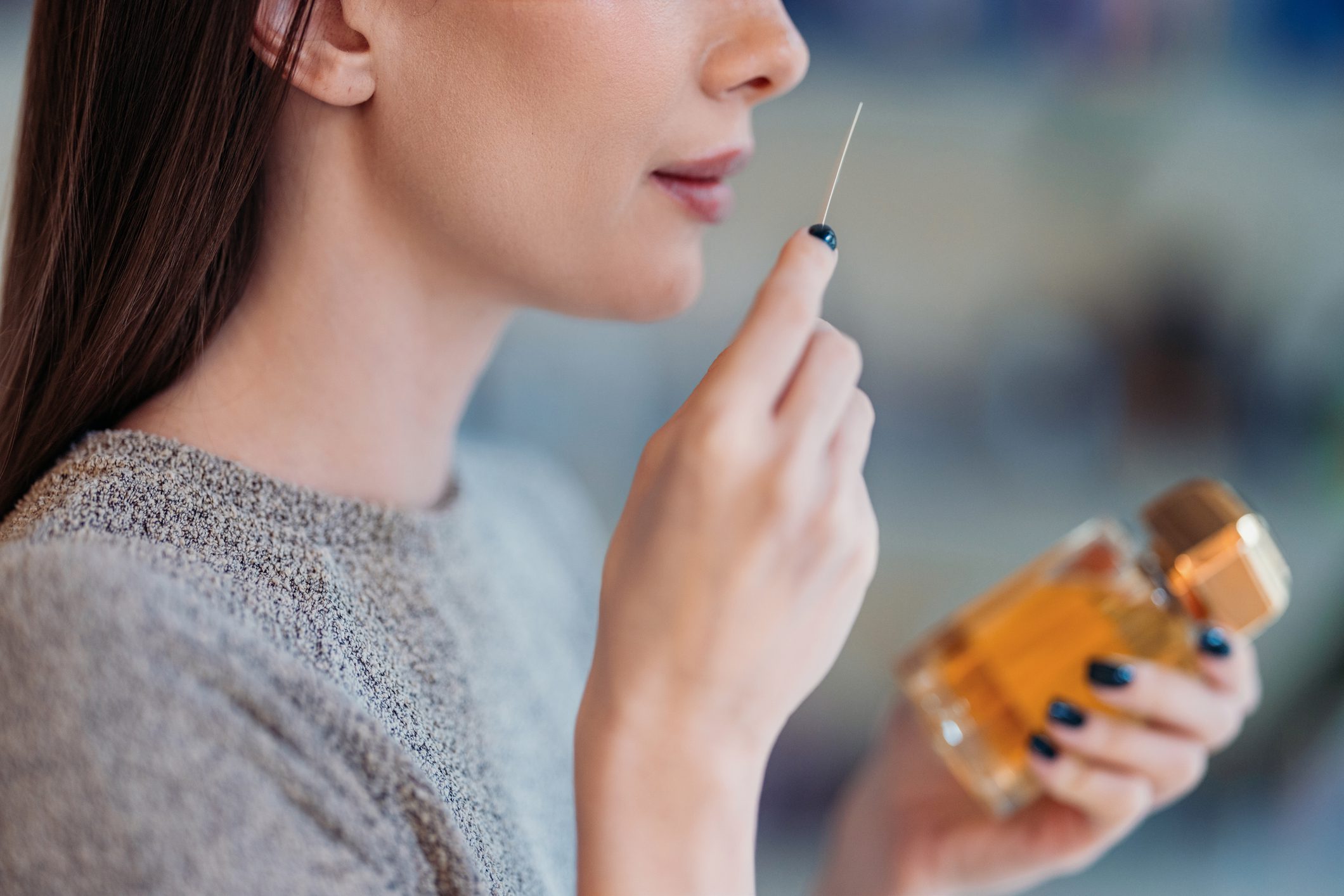 A woman smelling an essential oil bottle.